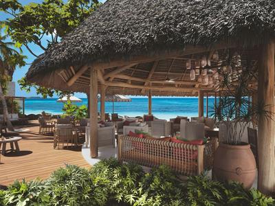 Pabellón abierto con techo de paja y área de descanso con vista al mar