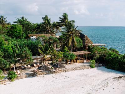 Resort de playa con palmeras, sillas de playa y vista al mar bajo cielo nublado