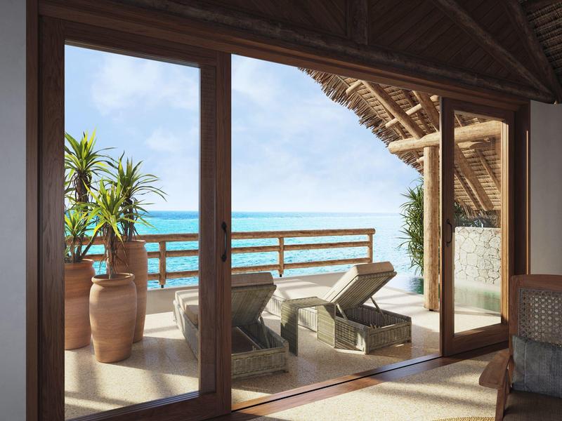 Balkon mit zwei Liegestühlen und Blick auf das Meer unter einem Strohdach.