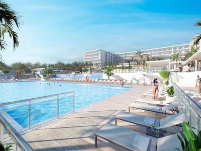 Duży basen hotelowy z leżakami i palmami w słoneczny dzień