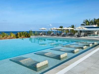 Piscine à débordement avec sièges encastrés et vue sur l'océan dans un complexe