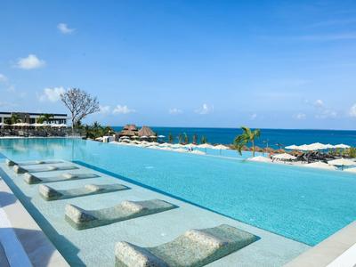 Piscine à débordement avec transats et vue sur la mer sous un ciel bleu