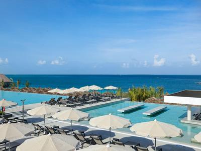 Moderní hotelový bazén s deštníky a lehátky s výhledem na moře za jasné oblohy