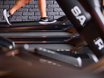Persona che corre su un tapis roulant in una palestra moderna con muro di mattoni.