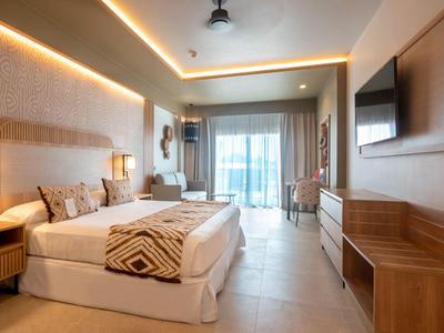 Camera d'hotel moderna con letto matrimoniale, scrivania e balcone con vista mare.