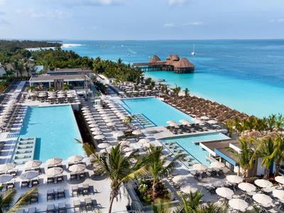 Grand complexe avec plusieurs piscines et de nombreux transats au bord de la mer.