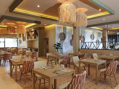 Intérieur de restaurant d'hôtel moderne avec des tons boisés et beiges, des lampes décoratives et des chaises rayées.