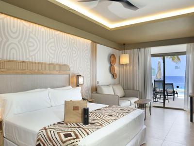 Chambre d'hôtel moderne avec lit double, canapé et terrasse vue mer