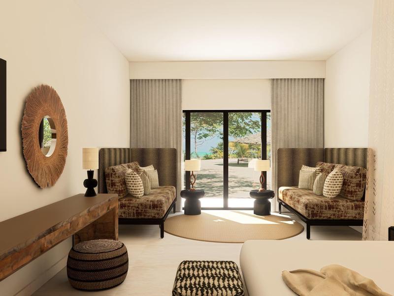 Helles Wohnzimmer mit zwei Sesseln, Rundteppich und Blick auf die Terrasse mit Meerblick.