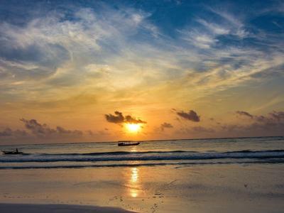 Zonsondergang boven rustige zee met boten en reflecterend zandstrand