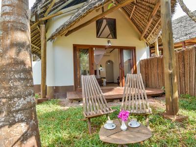 Gemütliche Außenbereich mit zwei Holzstühlen und Tisch vor einem tropischen Bungalow.