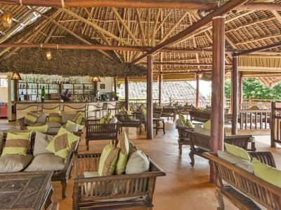 Offener Loungebereich mit Holzmöbeln und einem Strohdach in einem Urlaubsort