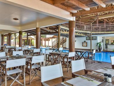 Interieur van een restaurant met witte stoelen en een blauw zwembad op de achtergrond