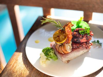 Elegantes Gourmetgericht mit Fleisch, gegrillter Zitrone und Kräutern auf weißem Teller.