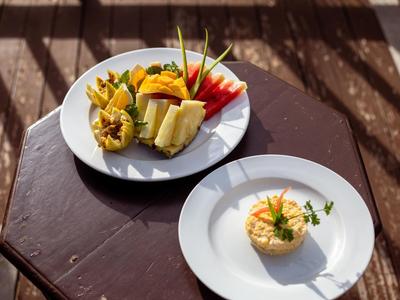 Zwei Teller mit frischem Obst und einer kunstvoll angerichteten Speise auf einem Holztisch im Freien.