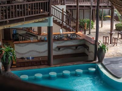 Poolbar met zitplaatsen in een tropisch resort met planten en houten meubels.