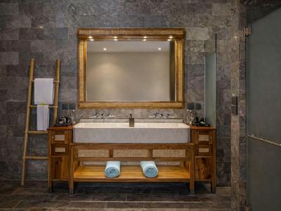 Bagno di lusso con mobile in legno, grande specchio e piastrelle in pietra