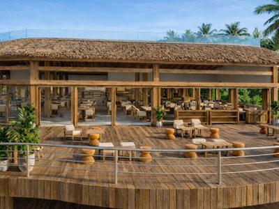 Ristorante in legno aperto con posti a sedere su una terrazza in un ambiente tropicale