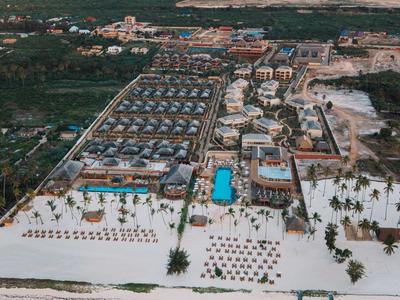 Vista aerea di un resort con piscina, spiagge di sabbia bianca e mare turchese.