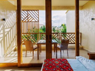 Vista attraverso grandi porte di vetro su balcone con mobili in legno e paesaggio verde.