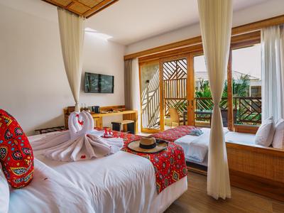 Camera d'hotel accogliente con letto matrimoniale, tessuto decorativo e balcone con vista sul verde.