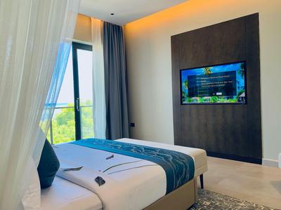 Nowoczesny pokój hotelowy z dwoma łóżkami, dużym oknem i telewizorem ściennym.