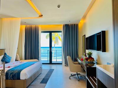 Nowoczesny pokój hotelowy z łóżkiem podwójnym, biurkiem, telewizorem i balkonem z widokiem na morze.