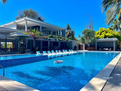 Nowoczesny basen hotelowy z leżakami i kwitnącą roślinnością pod czystym niebem.