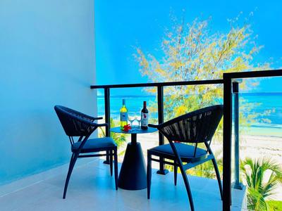 Balkon z dwoma krzesłami i stołem z butelkami wina i kieliszkami, widok na morze w słoneczny dzień.