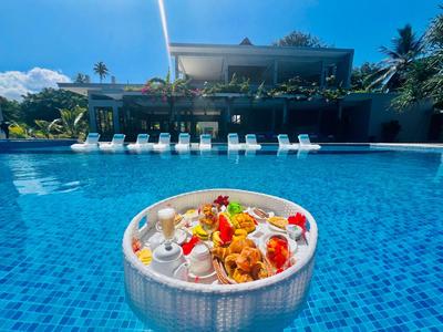 Miska z wodą i kwiatami przed basenem i leżakami w tropikalnym hotelu.