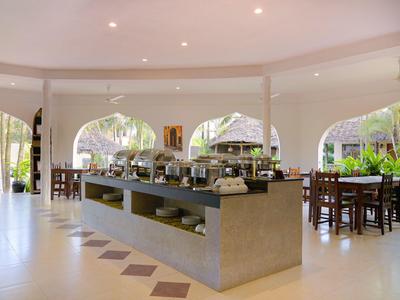 Heller, offener Buffetbereich in einem Hotel mit zentralem Buffettisch und Sitzplätzen im Hintergrund.