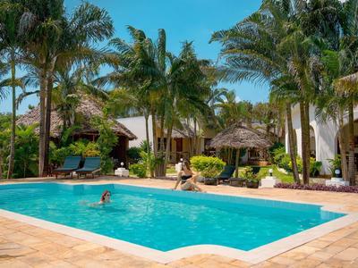 Hotelpool mit Menschen, umgeben von Palmen und tropischer Vegetation an einem sonnigen Tag