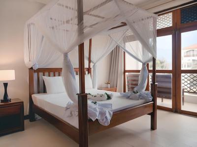 Elegantes Schlafzimmer mit Himmelbett, Nachtischlampen und Terrassentüren mit Blick nach draußen.