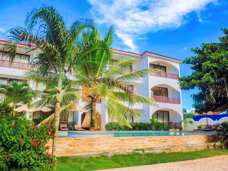 Moderner Hotelkomplex mit Palmen und klarer blauer Pool unter blauem Himmel