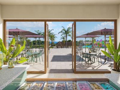 Blick aus einem hellen Raum auf eine Terrasse mit Tischen, Stühlen und Sonnenschirmen, Palmen im Hintergrund.