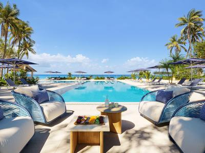 Luxuriöse Lounge-Sitze rund um Pool mit Blick auf Palmen und blaues Meer.