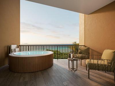 Balkon mit runder Badewanne und Sitzbereich mit Meerblick.