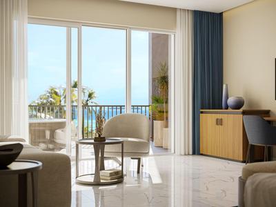 Helles Hotelzimmer mit Sitzbereich und Balkon mit Meerblick