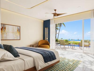 Modernes Hotelzimmer mit großem Bett, Sessel und Blick auf eine Terrasse mit Sitzgelegenheiten und Meer