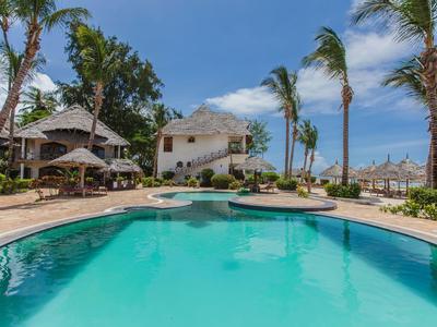 Gran piscina tropical con palmeras y un resort bajo un cielo azul.