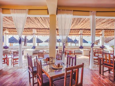 Restaurante luminoso con muebles de madera y vista a una terraza con sombrillas en la playa.