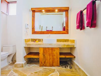 Área de baño luminosa con muebles de madera, espejo y toallas de colores en la pared.