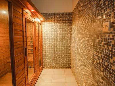 Área de spa iluminada con sauna de madera y paredes revestidas con mosaicos.