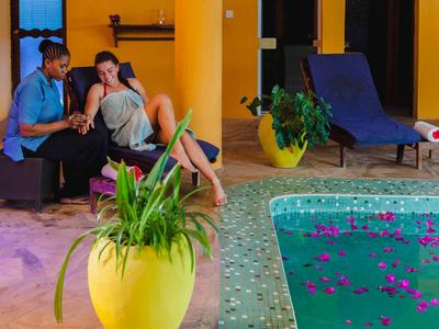 Pareja relajada junto a piscina con flores, ambiente tropical en entorno hotelero.