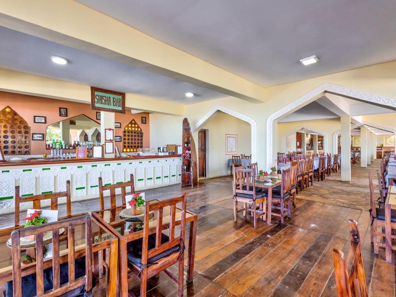 Restaurante luminoso con mesas y sillas de madera, barra grande y ambiente rústico.