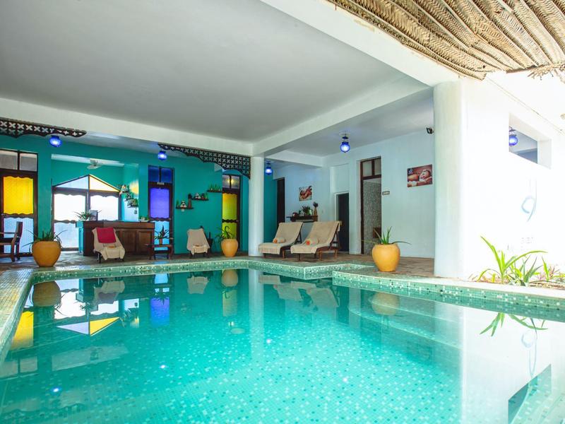 Piscina interior moderna con agua turquesa, áreas de descanso cómodas y paredes coloridas en un área del hotel.