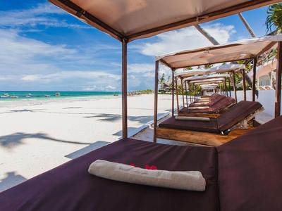 Strandliegen unter Überdachungen am weißen Sandstrand mit Blick auf das blaue Meer.