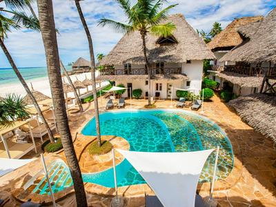 Ein Hotelpool mit Palmen und strohgedeckten Gebäuden am Strand bei sonnigem Wetter.