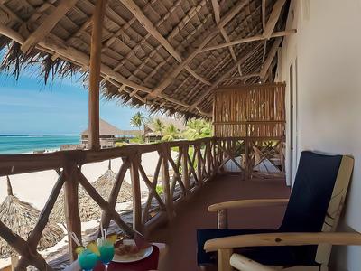 Veranda mit Holzstuhl und Tisch mit Blick auf tropischen Strand und Meer.