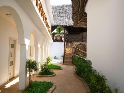 Innenhof mit weiß gestrichenen Wänden, Bögen, Pflanzen und einem schmalen gepflasterten Weg.